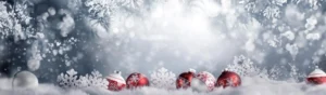 row of red and white ornaments nestled in snow fluff with bokeh lighting and pine boughs above